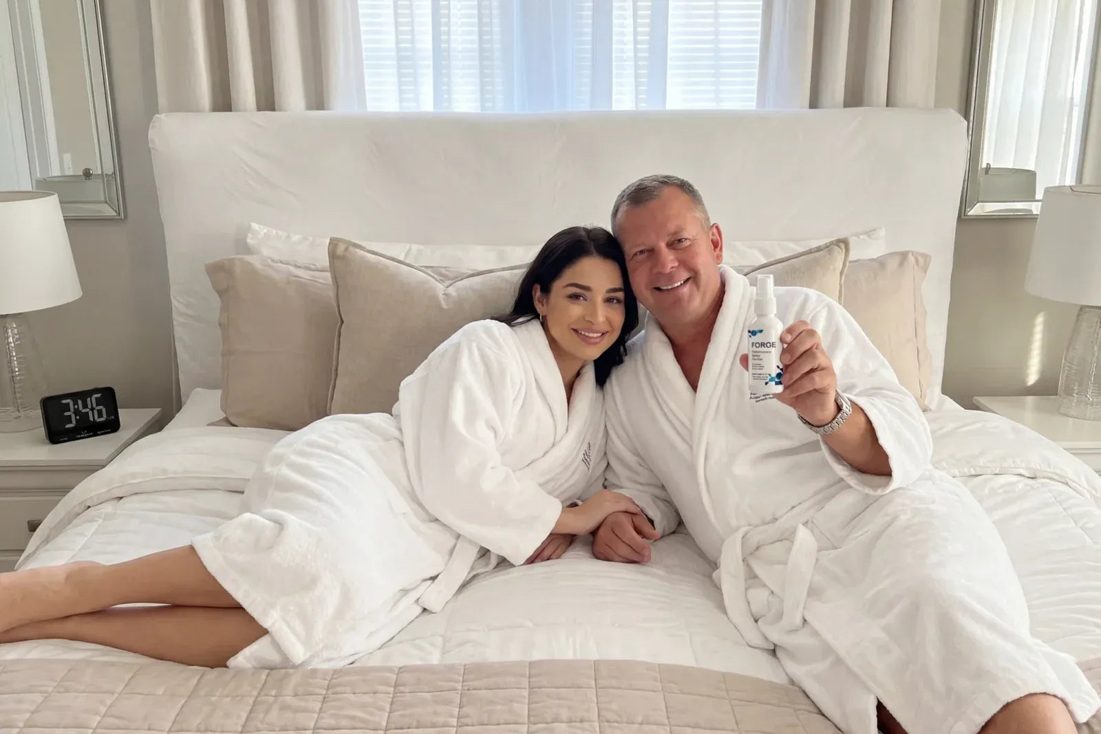 Couple in bathrobes holding FORGE on a bed